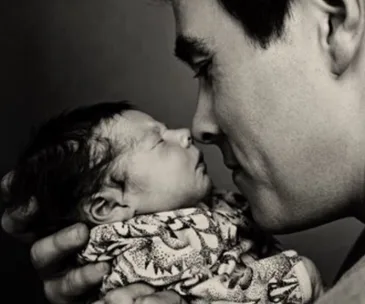 Father gently holding and gazing at a newborn baby, creating an intimate and tender moment.