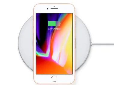iPhone 8 placed on a wireless charger, screen displaying 63% charged.