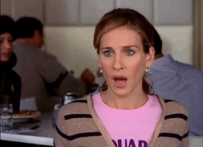 Carrie Bradshaw looks surprised in a cafe setting in "Sex and the City."