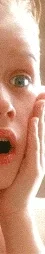 Child with hands on cheeks, surprised expression, from a famous holiday movie scene.