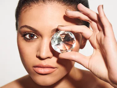 Woman holding a large diamond over her eye, highlighting transformation of ashes into diamonds.