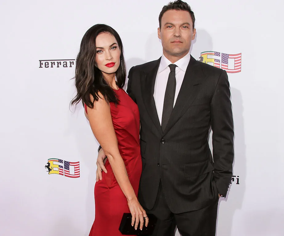 A couple posing at an event; woman in a red dress, man in a black suit.
