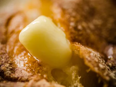 Close-up of a melting pat of butter on a slice of bread, highlighting its glossy texture.