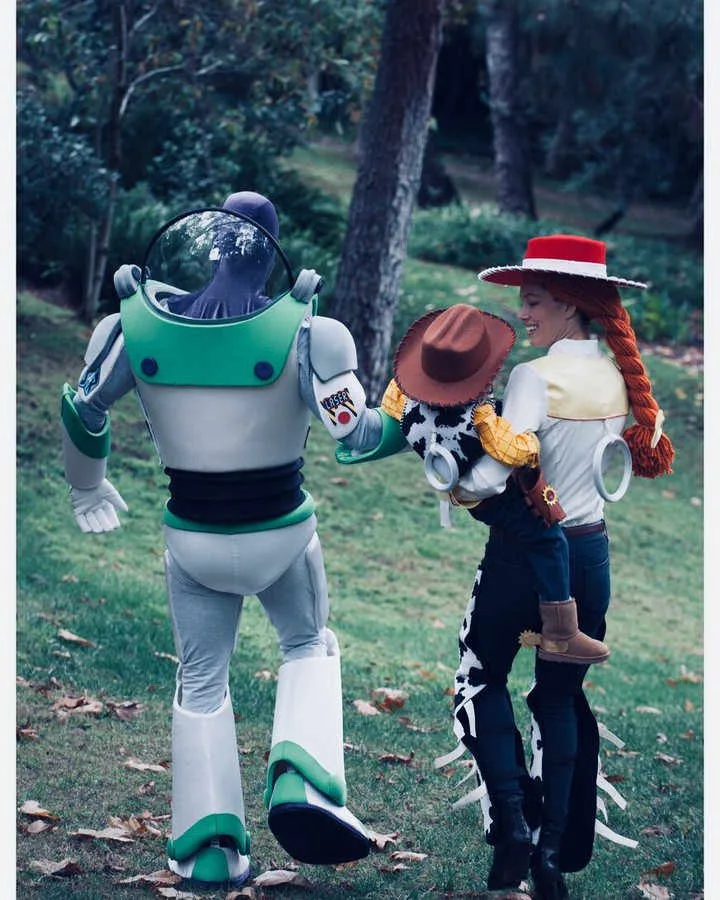 Family dressed as Buzz Lightyear, Jessie, and Woody from Toy Story walking in a park.