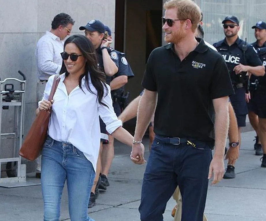 A couple holding hands, walking outdoors, both wearing sunglasses; surrounded by police officers.