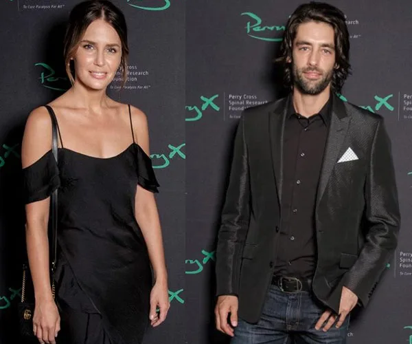 Two individuals posing at a Perry Cross event in formal attire, standing in front of a branded backdrop.