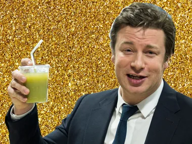 A person in a suit holding a green beverage in a plastic cup with a straw, against a sparkling gold background.