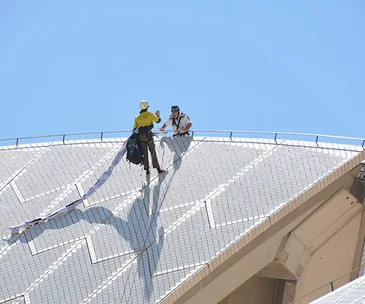 Protesters scale the Sydney Opera House with banners, highlighting the Manus Island humanitarian crisis.
