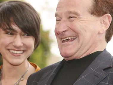 Two people smiling and laughing together outdoors.