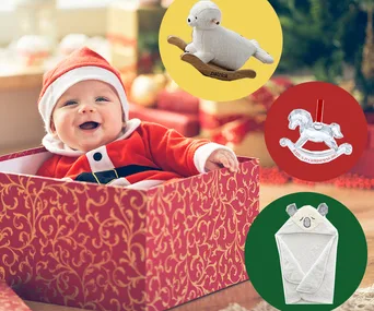 Baby in Santa outfit in a festive box with toy ideas: rocking lamb, crystal rocking horse, and koala towel.
