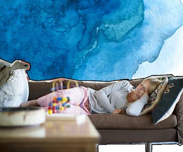 A person sleeping on a couch with blue abstract watercolor background.