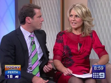 Two people sitting on a talk show set, engaged in conversation, with on-screen graphics showing time and temperature.