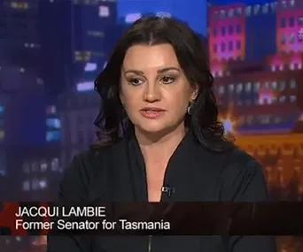 Jacqui Lambie in a TV interview, titled "Former Senator for Tasmania," with a cityscape backdrop.