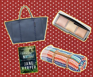 Gifts for a new mum: a blue bag, makeup palette, "Force of Nature" book, colorful blanket on red polka dot background.