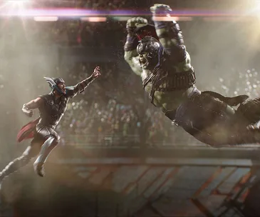 Thor and Hulk battling in an arena, with Thor mid-air ready to strike and Hulk charging in, surrounded by a cheering crowd.