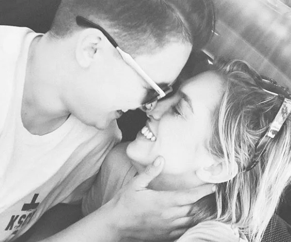 Two people smiling closely at each other, embracing affectionately in a grayscale photo.