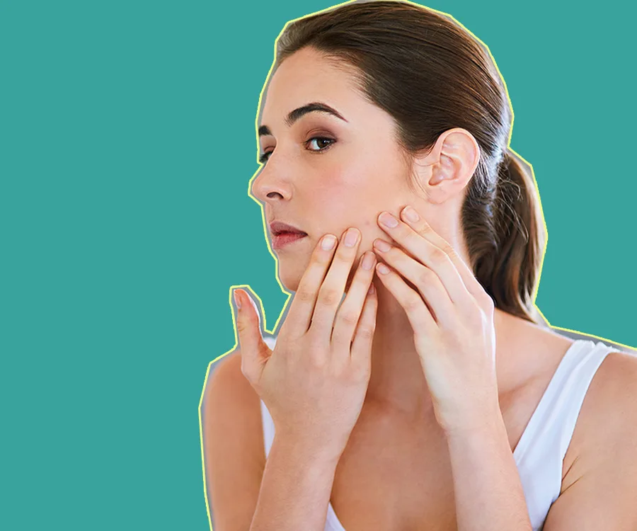 Woman examining her face for acne against a green background.
