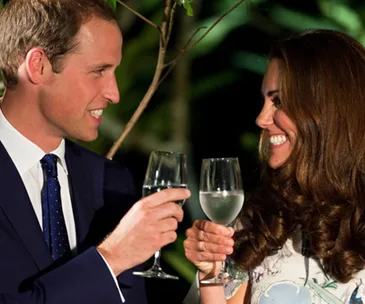 A man and woman toast with wine glasses in a festive setting, smiling at each other.