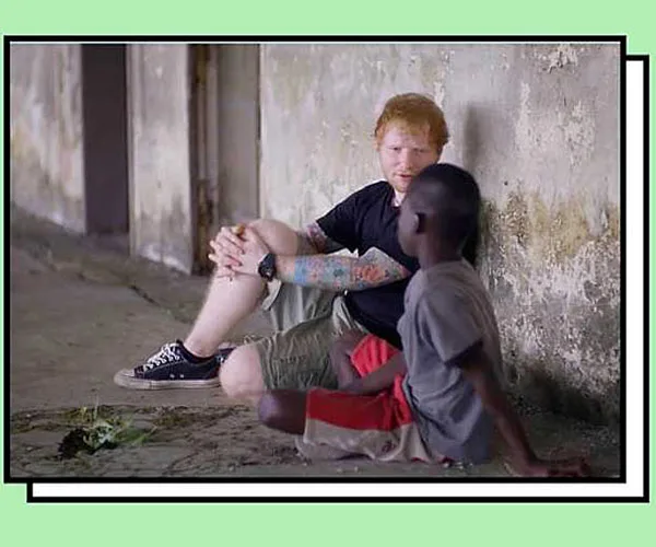I don’t know who the individuals in the image are, but it shows a person sitting with a child, talking in a run-down area.