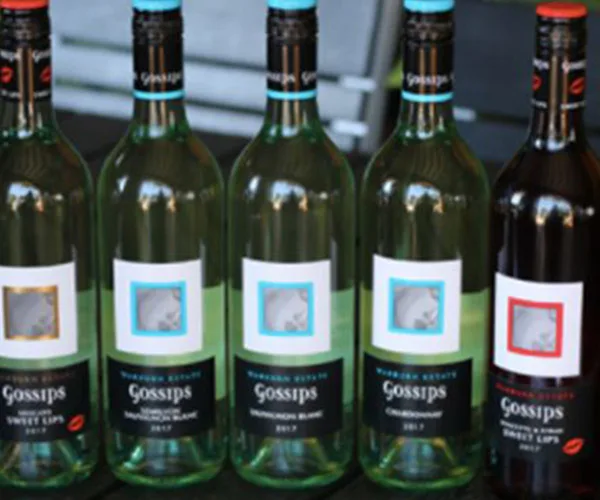 Five bottles of Gossips wine lined up with different colored labels on a table.