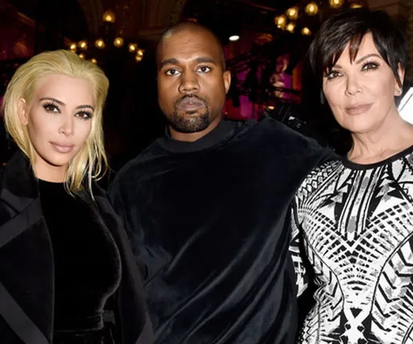 Kim, Kanye, and Kris at an event, dressed in formal wear with warm lighting in the background.