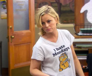 A person wearing a "I hate Mondays" Garfield T-shirt in an office setting.
