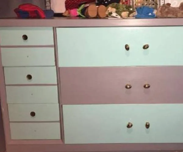 Chest of drawers with alternating teal and gray panels, with several items on top.
