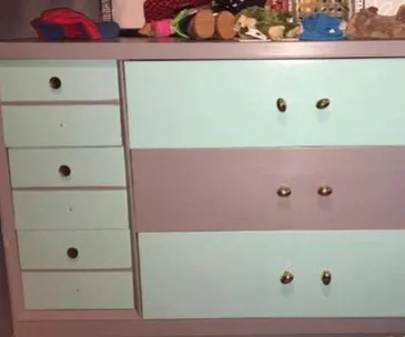 Chest of drawers with alternating teal and gray panels, with several items on top.