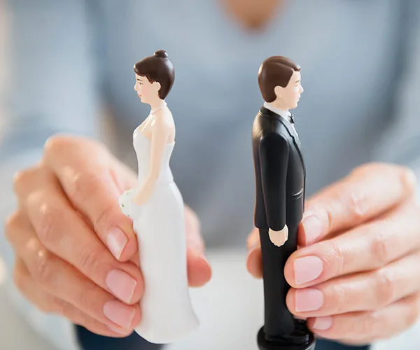 Hands separating bride and groom cake toppers, symbolizing conflict or separation.