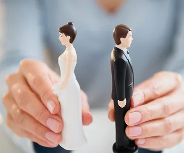Hands separating bride and groom cake toppers, symbolizing conflict or separation.
