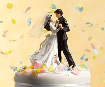 Bride and groom cake topper surrounded by colorful confetti on a wedding cake.