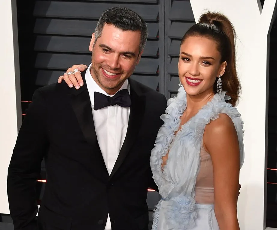 A man in a black suit and bow tie poses with a woman in a light blue dress at an event, both smiling.