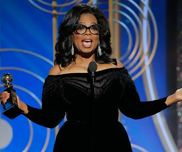 Oprah Winfrey on stage with Cecil B. DeMille Award at 2018 Golden Globes, delivering a speech in a black gown.