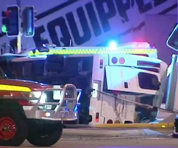 Emergency vehicles at night near an overturned truck with flashing lights.