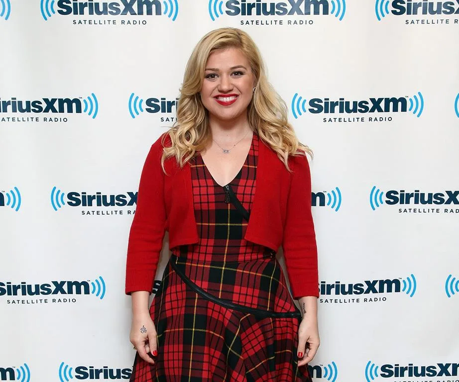 Singer in red plaid dress smiling in front of SiriusXM backdrop.