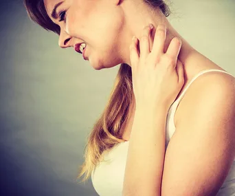 Woman scratching her neck, showing discomfort likely due to eczema symptoms.