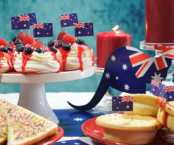 Australian-themed desserts with flag picks, a candle, and kangaroo cutout on a table setting.