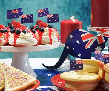 Australian-themed desserts with flag picks, a candle, and kangaroo cutout on a table setting.
