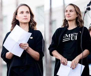 Natalie Portman speaking at an outdoor event, holding a paper, wearing a "Time's Up" T-shirt and black cardigan.