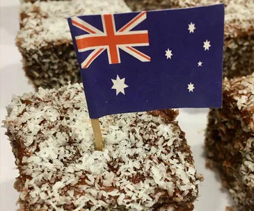 A lamington topped with coconut flakes, featuring an Australian flag toothpick.