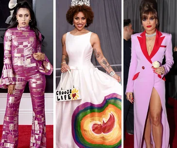 Three women on the red carpet in unique outfits, including a pink suit, a white gown with a message, and a two-tone dress.