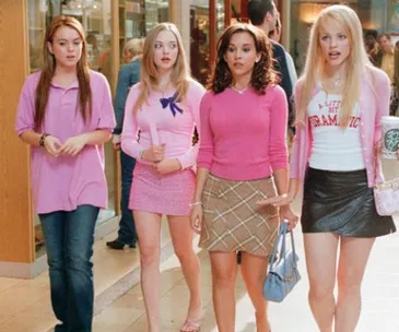 Four young women in stylish pink outfits walking confidently in a mall setting.