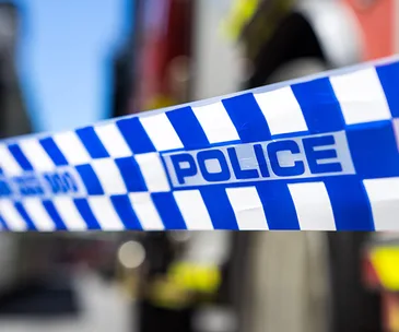 Police tape with blue and white checks cordoning off an area, with blurred background.