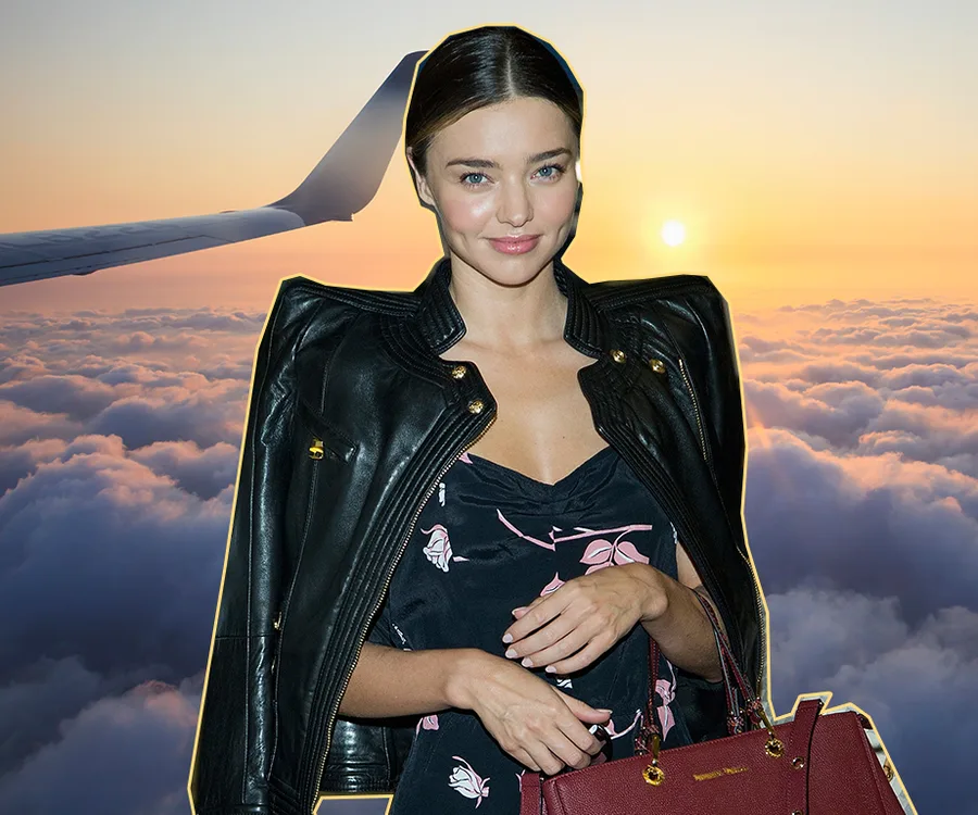 Woman in a floral dress and leather jacket posing with clouds and airplane wing in the background at sunset.