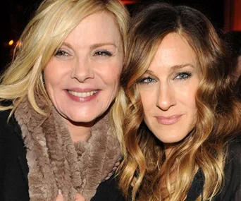 Two women, smiling together, one with blonde hair and a fur scarf, the other with wavy hair.