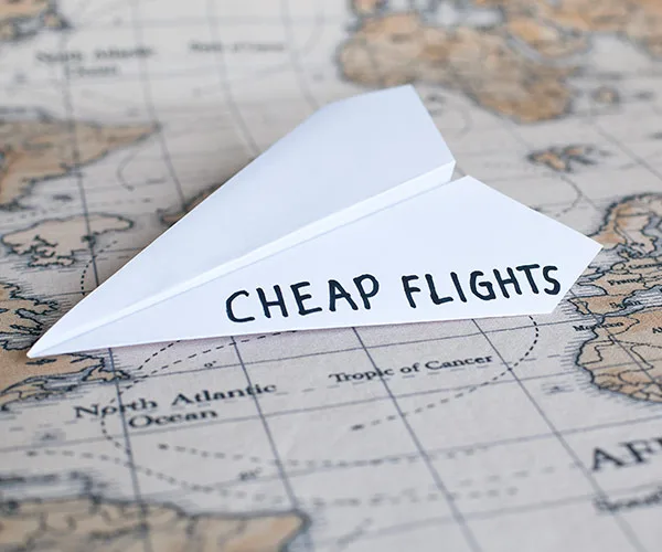 Paper plane labeled "Cheap Flights" on world map background.