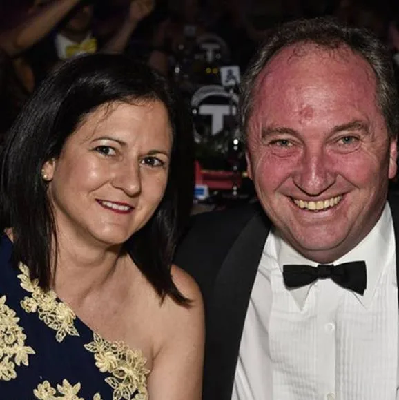 A smiling couple dressed formally, sitting together at an event.