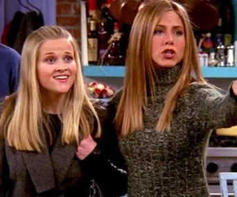 Two women from "Friends," one pointing and the other smiling, in a kitchen setting.