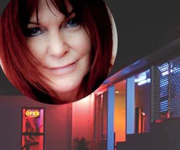 Headshot of a woman with red hair overlaid on a building with neon lights at night.