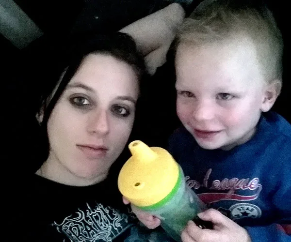 A woman and young child lie together; the child holds a sippy cup.